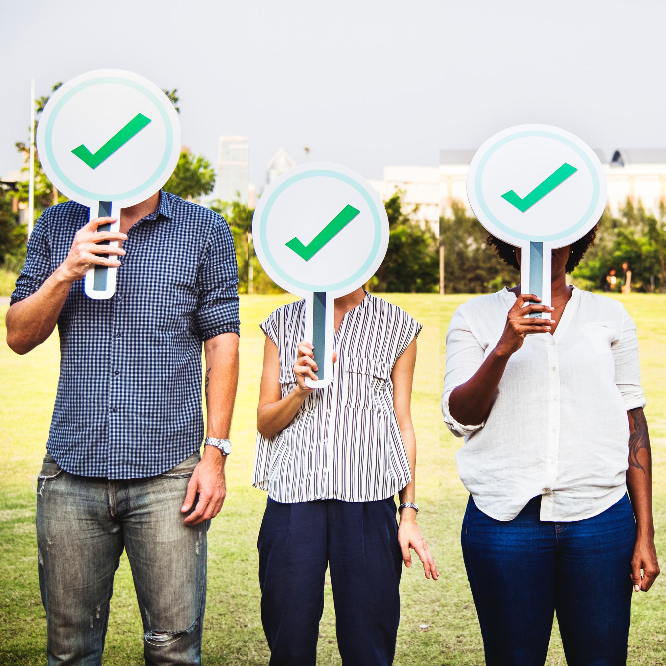 "diverse group holding signs with green checkmark"